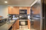 Galley kitchen with full size appliances, custom cabinets, and granite counters